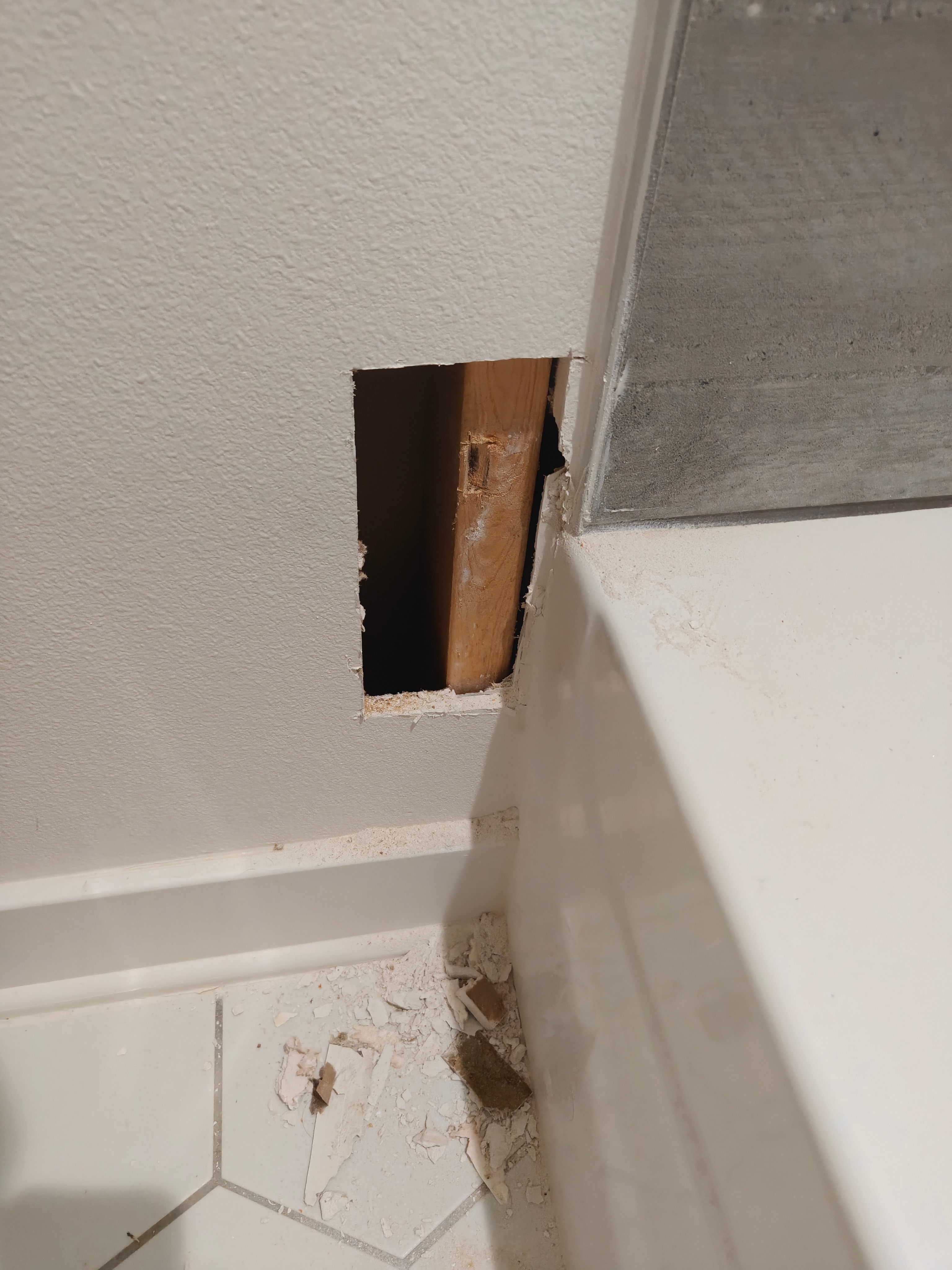 Drywall access opening cut near baseboard exposing wall stud in Fayetteville